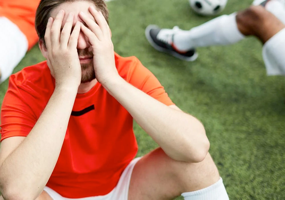 footballer on pitch with head in hands